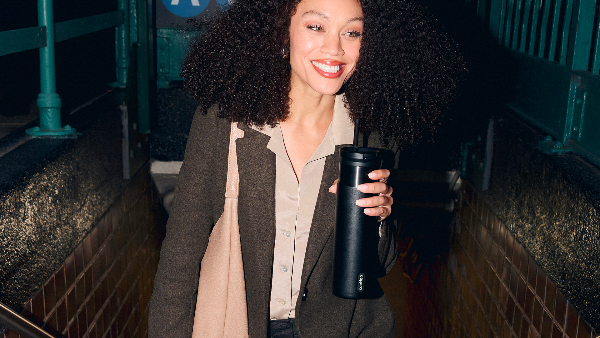 A woman holding a black Contigo bottle on city stairs
